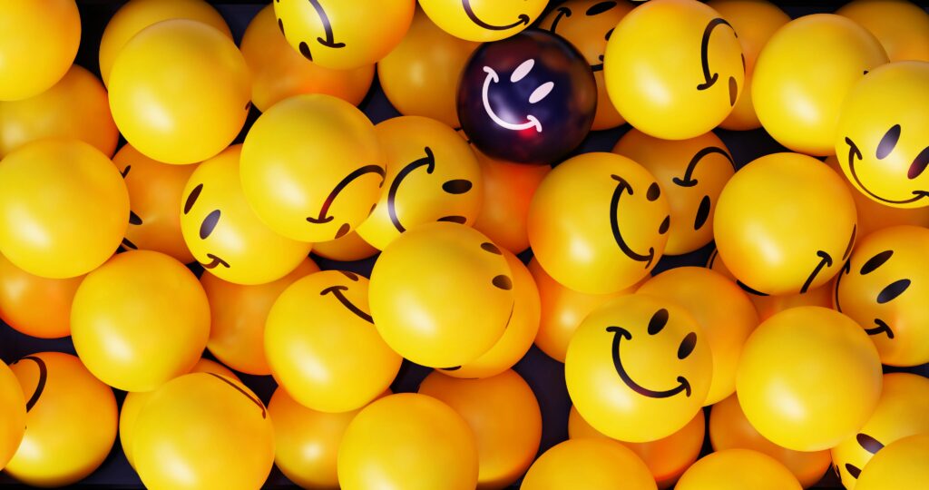 A vibrant collection of yellow smiley face balloons with one unique dark balloon.